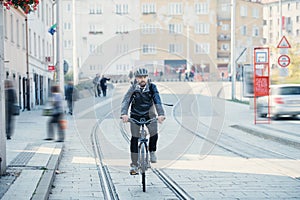 Hipster businessman commuter with electric bicycle traveling home from work in city.