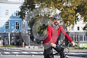 Hipster businessman commuter with electric bicycle traveling to work in city.