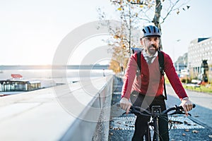 Hipster businessman commuter with electric bicycle traveling to work in city.