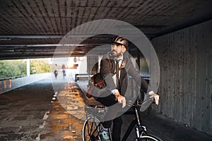 Hipster businessman commuter with electric bicycle traveling to work in city.