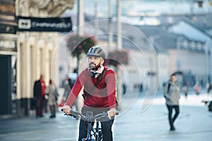 Hipster businessman commuter with electric bicycle traveling to work in city.