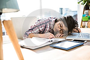 Hipster businessman falling asleep on desk