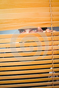 Hipster businessman peeking through blinds