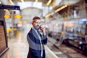 Hipster businessman with smartphone, making a phone call, platform