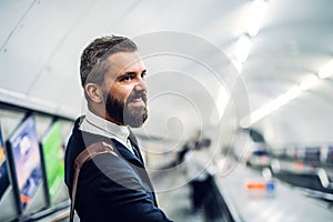 Hipster businessman using escalator in subway, travelling to work.