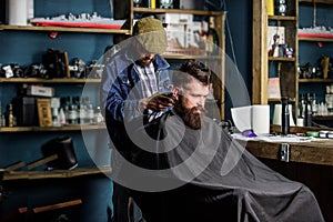 Hipster client getting haircut. Barber with hair clipper works on haircut of bearded guy barbershop background. Barber