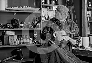 Hipster client getting haircut. Barber with hair clipper works on haircut of bearded guy barbershop background. Hipster