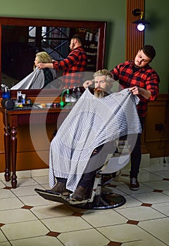 Hipster client getting haircut. Barber and hair stylist dedicate to making you better looking person. Barber with photo