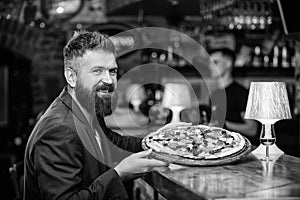 Hipster client sit at bar counter. Man received delicious pizza. Enjoy your meal. Cheat meal concept. Hipster hungry eat