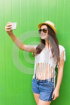 Hipster cool girl taking picture on smartphone self-portrait