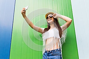 Hipster cool girl taking picture on smartphone self-portrait