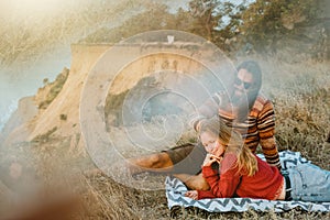 Hipster couple chilling and hugging on blanket on rocky coast wi