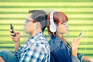 Hipster couple in disinterest moment with mobile smart phones