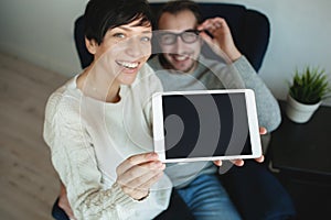 Hipster couple in eyewear showing the screen of tablet