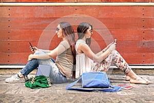 Hipster couple of girlfriends in disinterest moment with phones
