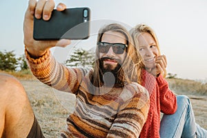 Hipster couple in sweaters making selfie outdoors