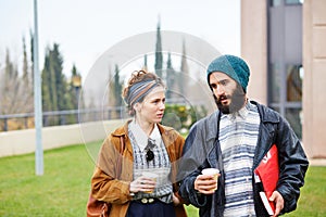 Hipster couple talking and drinking coffee to go