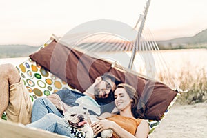 Hipster couple on a trip to the beach, young freelancer man relaxing in a hammock with his woman, romantic couple on vacation with