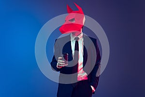 Hipster. Creative portrait of young stylish man in business suit with cardboard mask on his head isolated on dark blue