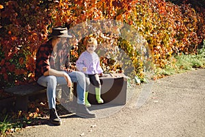 An hipster dad with son on a walk in nature at sunset. Full-length portrait of a bearded man and his son in the autumn