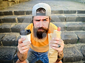 Hipster enjoy hot dog and drink paper cup beverage. Fast food for lunch common idea. Man bearded enjoy street food