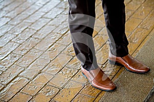 Hipster fashion man`s legs in black jeans and brown leather