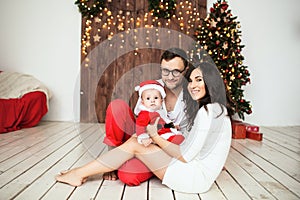 Hipster father and mother holding baby in santa suit