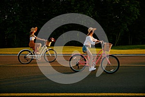 Hipster female friends cycling together along local road