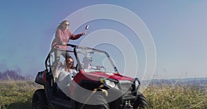 Hipster friends having fun with color flares and while driving off road car in nature. Adventurous spirit and freedom