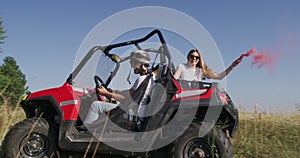 Hipster friends having fun with color flares and while driving off road car in nature. Adventurous spirit and freedom