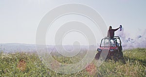 Hipster friends having fun with color flares and while driving off road car in nature. Adventurous spirit and freedom