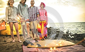 Hipster friends having fun walking with led neon lanterns at beach camping party - Friendship travel concept with young wanderer