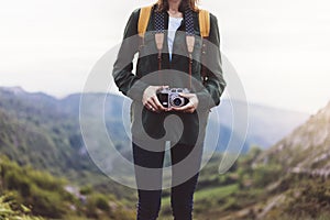 Hipster girl with backpack enjoying sunset on peak of foggy mountain, tourist traveler taking pictures of amazing landscape