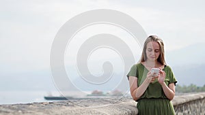 Hipster girl with backpack hold on smart phone gadget in sand coastline. Traveler using in female hand mobile on