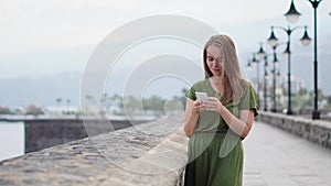 Hipster girl with backpack hold on smart phone gadget in sand coastline. Traveler using in female hand mobile on