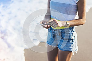 Hipster girl hold on smart phone gadget in sand coastline, mock up of blank screen. Traveler using in female hand mobile on back