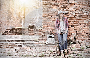 Hipster girl leaning against the old temple wall.