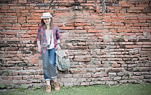 Hipster girl leaning against the old temple wall.