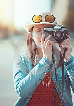 Hipster girl making picture with retro camera, focus on camera