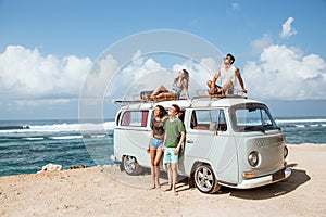 Hipster girl relaxing with friends on the retro van roof