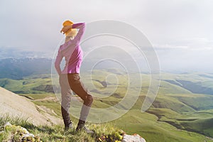 A hipster girl in a straw hat and glasses on the nature landscape