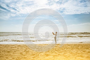 Hipster girl is taking selfie at the beach. Big waves at the ocean side. Coastline in the clouds and sun. Summer vacation. Travel