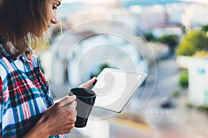 Hipster girl using tablet technology and drink coffee, girl person holding computer on background sun city, female hands texting m