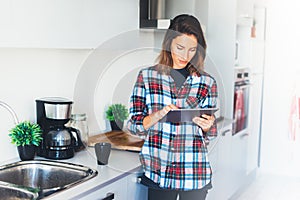 Hipster girl using tablet technology and drink coffee in kitchen, girl person holding computer on background interior cuisine, fem