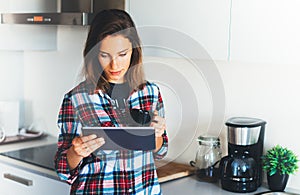 Hipster girl using tablet technology and drink coffee in kitchen, girl person holding computer on background interior cuisine, fem