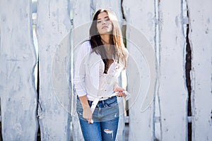 Hipster girl wearing blank white shirt and jeans posing against street wall. Minimalist urban clothing style, street