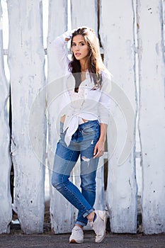 Hipster girl wearing blank white shirt and jeans posing against street wall. Minimalist urban clothing style, street