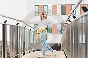 Hipster girl wearing blank white t-shirt and jeans posing against street road, minimalist urban clothing style.