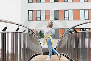 Hipster girl wearing blank white t-shirt and jeans posing against street road, minimalist urban clothing style.