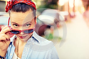 Hipster girl wearing sunglasses and fashion accessories. Smiling girl making funny faces in lifestyle portrait